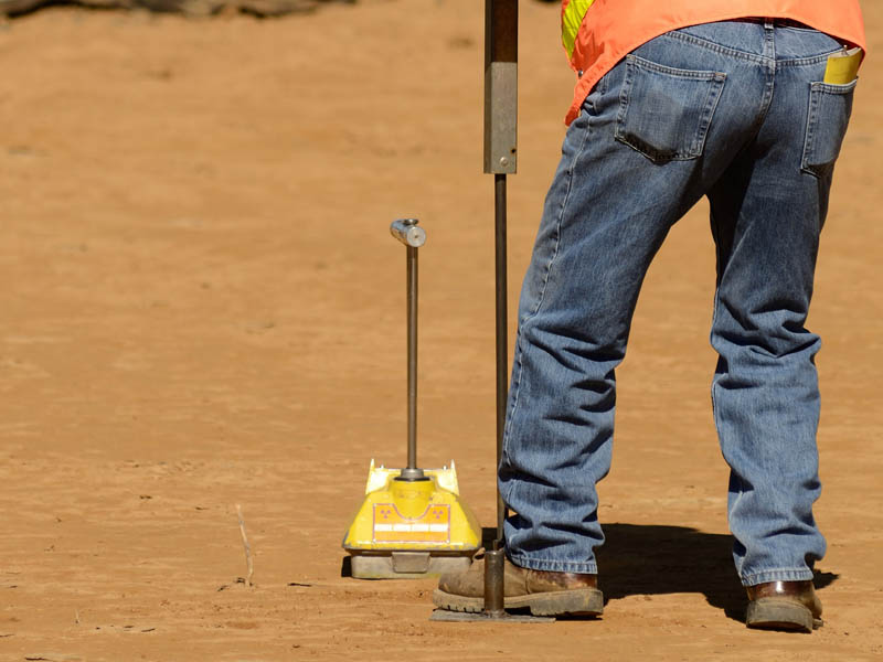 Field engineer using a Nuclear Density Gauge to check for soil d